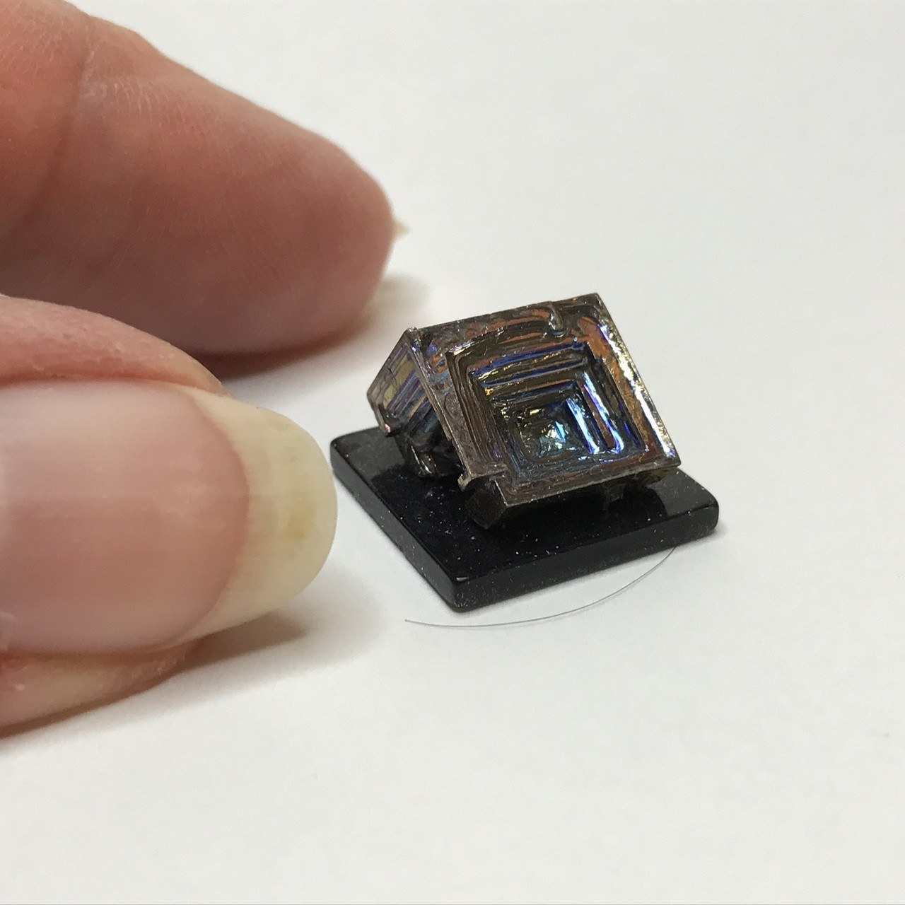 Crystalline Bismuth miniature sculpture shown with fingers for scale