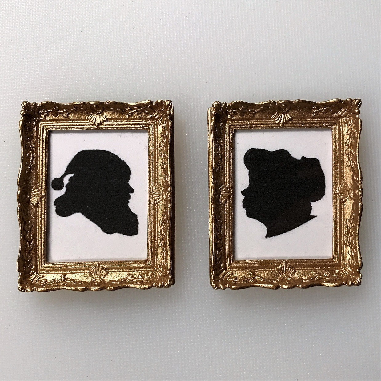 Dollhouse miniature Santa and Mrs. Claus silhouettes in ornate, gold-tone picture frames