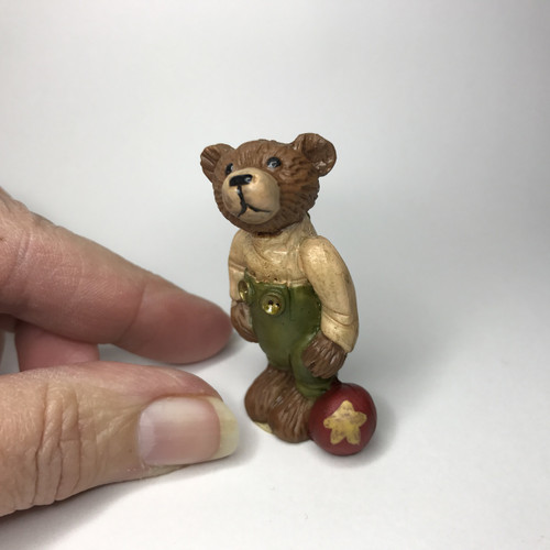 Standing bear with green pants and a ball at his feet.