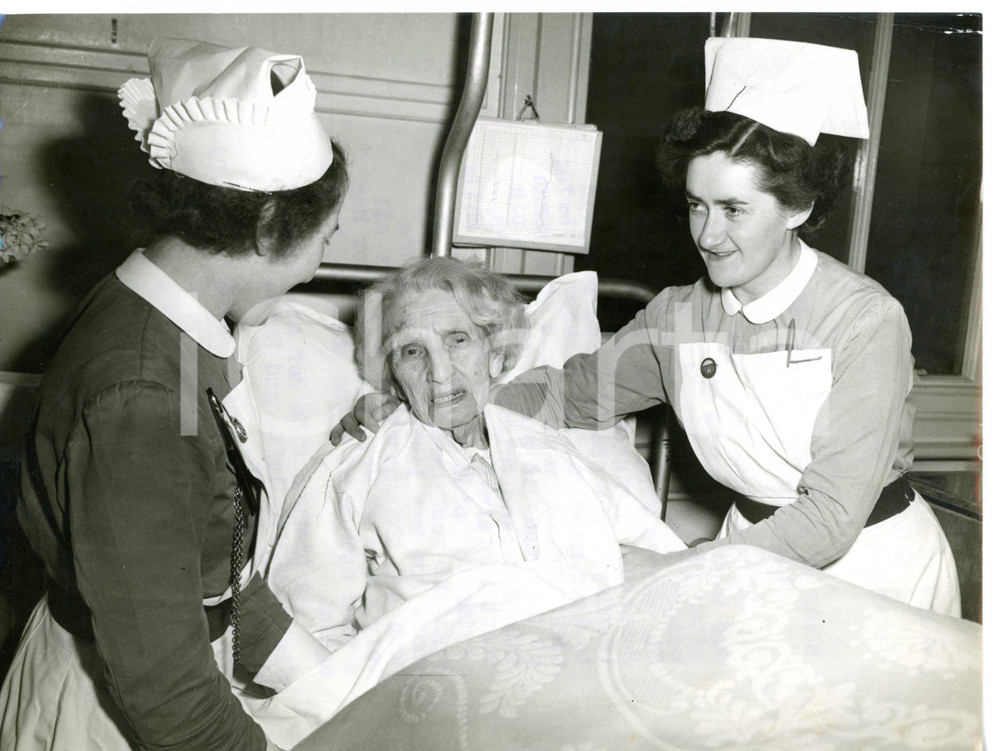 1953 LONDON Whittington Hospital - Woman of 102 years after operation *Foto  Fotografia d'epoca con didascalia coeva. CONDIZIONI: FAIR (piccole piegature ai margini; timbro al verso sovraimpresso; strappo millimetrico al margine sinistro)DIMENSIONI: 20x15 cm     originale e autentica 1