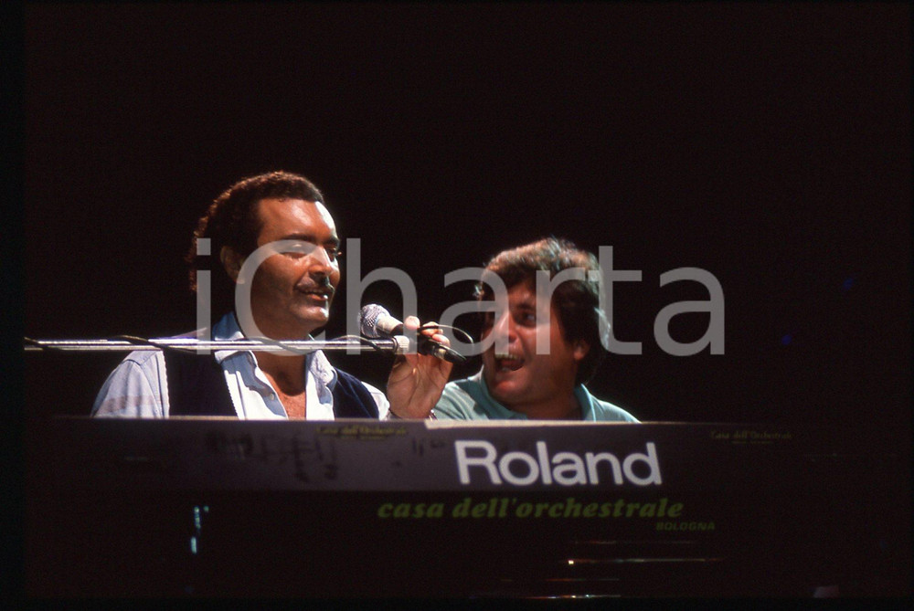35mm vintage slide*1990ca BOLOGNA Diego ABATANTUONO Mauro DI FRANCESCO al piano   Diapositiva d'epoca, in formato 35 mm. CONDIZIONI: GOODE' severamente vietata la riproduzione. Tutti i diritti sono riservati. ICharta mette in vendita, sul negozio eBay e in esclusiva sul sito "icharta" il proprio archivio composto da numerose diapositive e negativi fotografici d'epoca, tutti originali e autentici, che attraversano la storia del costume italiano tra gli la fine degli anni Sessanta e Novanta.Si tratta di uno sguardo inedito sull'attualit&agrave;, la politica, la vita quotidiana, il gossip e la cultura, che fotografa il cambiamento della nazione in quest'ultimo scorcio del XX secolo. Un'occasione unica per il mercato del collezionismo, che vede finalmente disponibile un archivio eccezionale per vastit&agrave;, tematiche e condizioni, in un settore (il negativo fotografico e la diapositiva) di assoluta novit&agrave; e dalle interessanti prospettive di investimento.  originale e autentica 1