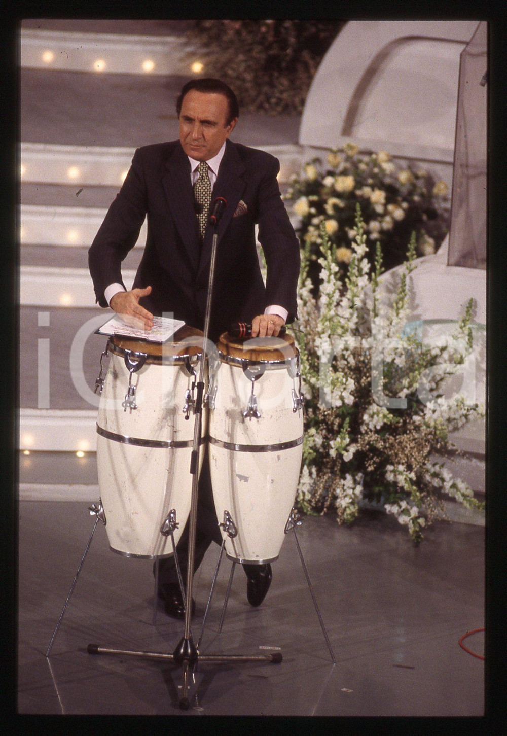 35mm vintage slide* 1990ca FESTIVAL DI SANREMO Pippo BAUDO con le conga   Diapositiva d'epoca, in formato 35 mm. CONDIZIONI: GOODE' severamente vietata la riproduzione. Tutti i diritti sono riservati. ICharta mette in vendita, sul negozio eBay e in esclusiva sul sito "icharta" il proprio archivio composto da numerose diapositive e negativi fotografici d'epoca, tutti originali e autentici, che attraversano la storia del costume italiano tra gli la fine degli anni Sessanta e Novanta.Si tratta di uno sguardo inedito sull'attualit&agrave;, la politica, la vita quotidiana, il gossip e la cultura, che fotografa il cambiamento della nazione in quest'ultimo scorcio del XX secolo. Un'occasione unica per il mercato del collezionismo, che vede finalmente disponibile un archivio eccezionale per vastit&agrave;, tematiche e condizioni, in un settore (il negativo fotografico e la diapositiva) di assoluta novit&agrave; e dalle interessanti prospettive di investimento.  originale e autentica 1