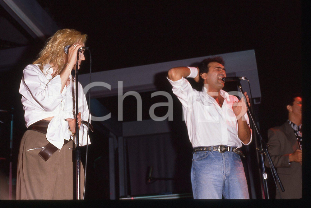 35mm vintage slide* 1990ca Anna OXA e Gianni BELLENO in concerto   Diapositiva d'epoca, in formato 35 mm. CONDIZIONI: GOODE' severamente vietata la riproduzione. Tutti i diritti sono riservati. ICharta mette in vendita, sul negozio eBay e in esclusiva sul sito "icharta" il proprio archivio composto da numerose diapositive e negativi fotografici d'epoca, tutti originali e autentici, che attraversano la storia del costume italiano tra gli la fine degli anni Sessanta e Novanta.Si tratta di uno sguardo inedito sull'attualit&agrave;, la politica, la vita quotidiana, il gossip e la cultura, che fotografa il cambiamento della nazione in quest'ultimo scorcio del XX secolo. Un'occasione unica per il mercato del collezionismo, che vede finalmente disponibile un archivio eccezionale per vastit&agrave;, tematiche e condizioni, in un settore (il negativo fotografico e la diapositiva) di assoluta novit&agrave; e dalle interessanti prospettive di investimento.     originale e autentica 1