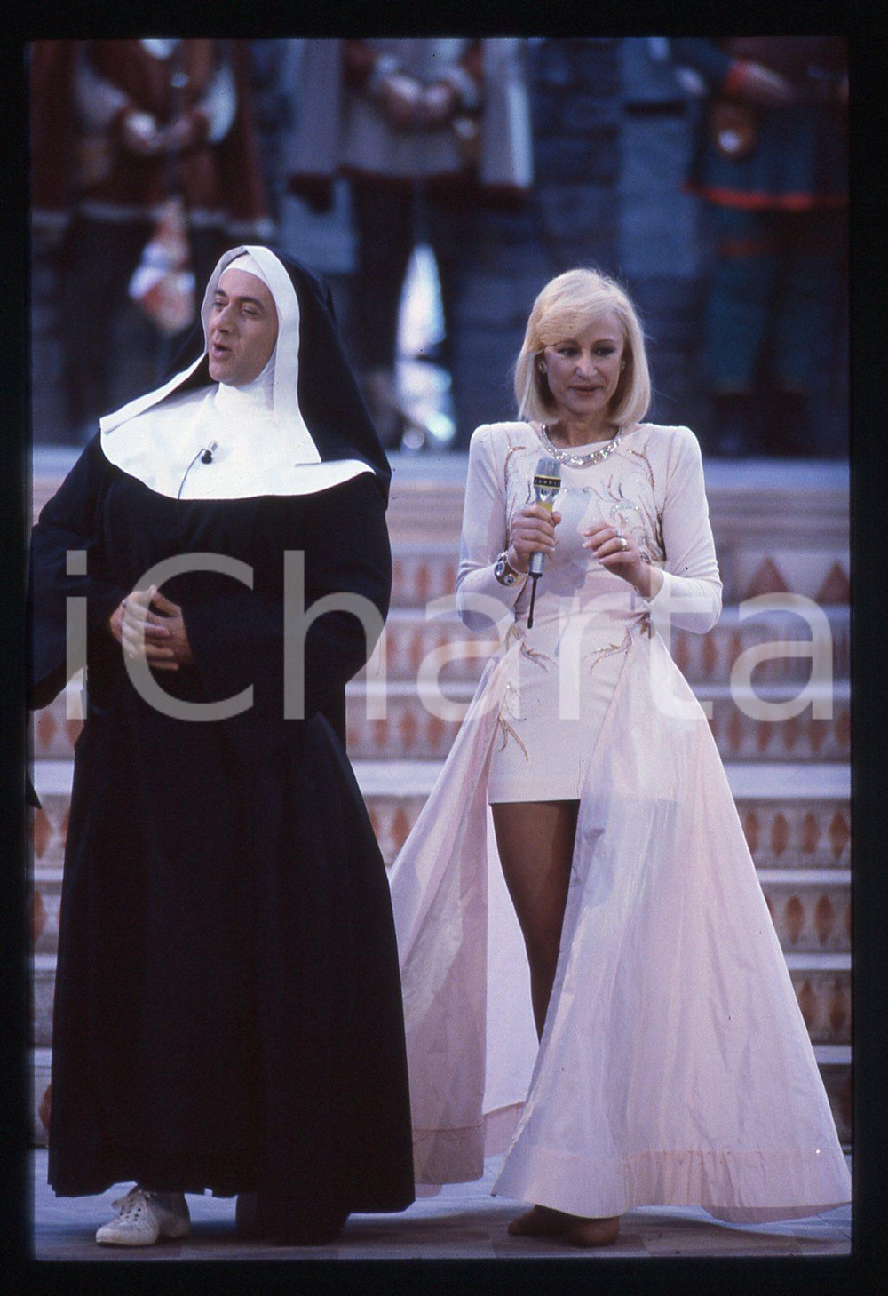 35mm vintage slide* 1991 SAINT VINCENT -  Raffaella CARRA' e Giorgio FALETTI   Diapositiva d'epoca, in formato 35 mm.Nella diapositiva Raffaella Carr&agrave; e Giorgio Faletti nei panni di Suor Daliso. CONDIZIONI: GOODE' severamente vietata la riproduzione. Tutti i diritti sono riservati. ICharta mette in vendita, sul negozio eBay e in esclusiva sul sito "icharta" il proprio archivio composto da numerose diapositive e negativi fotografici d'epoca, tutti originali e autentici, che attraversano la storia del costume italiano tra gli la fine degli anni Sessanta e Novanta.Si tratta di uno sguardo inedito sull'attualit&agrave;, la politica, la vita quotidiana, il gossip e la cultura, che fotografa il cambiamento della nazione in quest'ultimo scorcio del XX secolo. Un'occasione unica per il mercato del collezionismo, che vede finalmente disponibile un archivio eccezionale per vastit&agrave;, tematiche e condizioni, in un settore (il negativo fotografico e la diapositiva) di assoluta novit&agrave; e dalle interessanti prospettive di investimento.  originale e autentica 1
