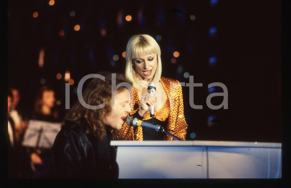 35mm vintage slide* 1988 RAFFAELLA CARRA' SHOW Raffaella CARRA' e Umberto TOZZI   Diapositiva d'epoca, in formato 35 mm. CONDIZIONI: GOODE' severamente vietata la riproduzione. Tutti i diritti sono riservati. ICharta mette in vendita, sul negozio eBay e in esclusiva sul sito "icharta" il proprio archivio composto da numerose diapositive e negativi fotografici d'epoca, tutti originali e autentici, che attraversano la storia del costume italiano tra gli la fine degli anni Sessanta e Novanta.Si tratta di uno sguardo inedito sull'attualit&agrave;, la politica, la vita quotidiana, il gossip e la cultura, che fotografa il cambiamento della nazione in quest'ultimo scorcio del XX secolo. Un'occasione unica per il mercato del collezionismo, che vede finalmente disponibile un archivio eccezionale per vastit&agrave;, tematiche e condizioni, in un settore (il negativo fotografico e la diapositiva) di assoluta novit&agrave; e dalle interessanti prospettive di investimento.  originale e autentica 1