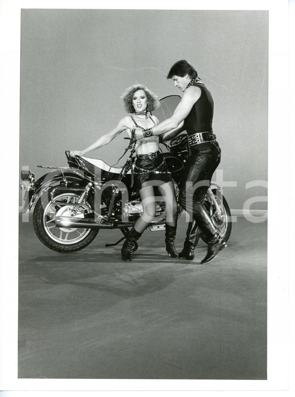 1983 LORETTA GOGGI IN QUIZ Loretta GOGGI Gianni BREZZA vestiti da motociclisti 1 Fotografia di agenzia. CONDIZIONI: G (ma lievi difetti di stampa; piccola piegatura all'angolo inferiore sinistro)FORMATO: 18x24 cm     originale e autentica 1