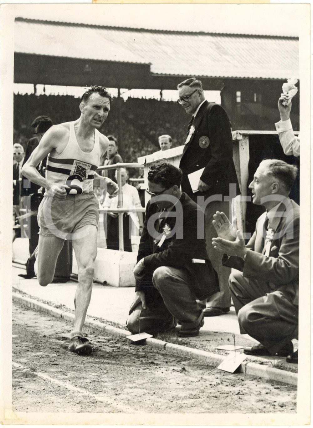 1953 LONDON White City Stadium - Jim PETERS One hour run record at BRITISH GAMES Fotografia d'epoca con didascalia coeva al verso.  CONDIZIONI: POOR (lievi sovraimpressioni; aloni ai margini; piccolo residuo di incollatura all'angolo inferiore sinistro; vari graffi e macchie) FORMATO: 15x20 cm     originale e autentica 1