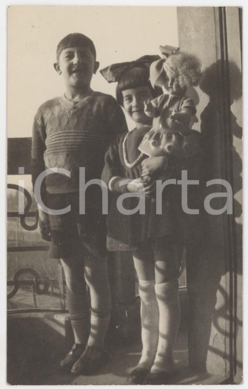 1925 ca COSTUME Ritratto di due fratellini con la bambola - Fotocartolina 8x13