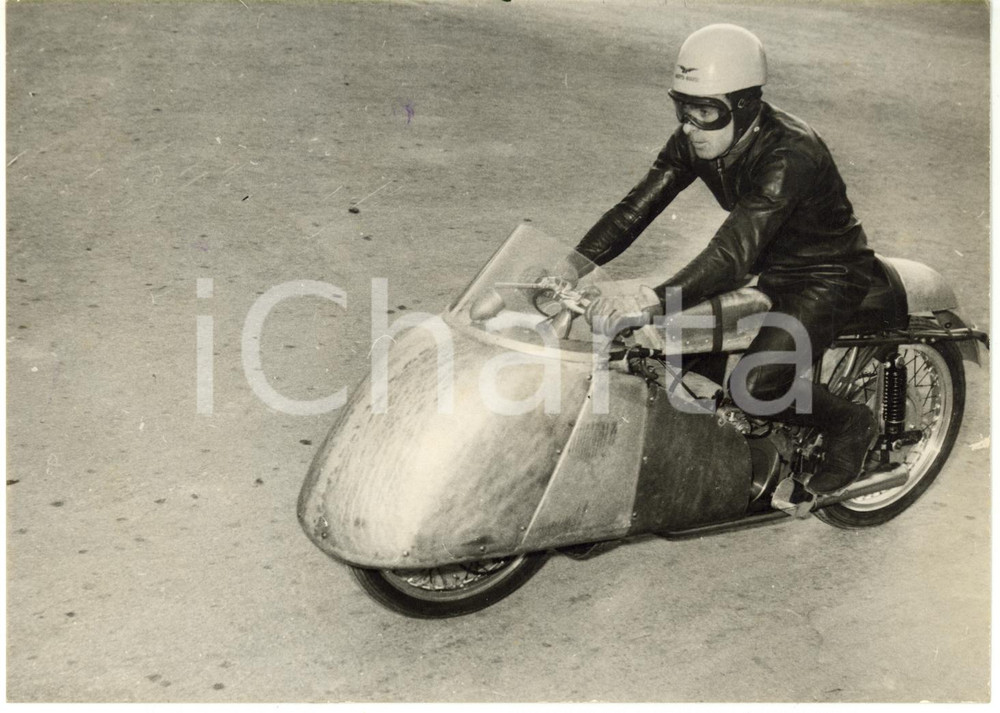 1954 CIRCUITO OSPEDALETTI Ken KAVANAGH testa nuova MOTO GUZZI 500 cc carenata  Fotografia d'epoca con didascalia al verso.  CONDIZIONI: G (lievi difetti di stampa; minima traccia di inchiostro blu) FORMATO: 18x13 cm     originale e autentica 1
