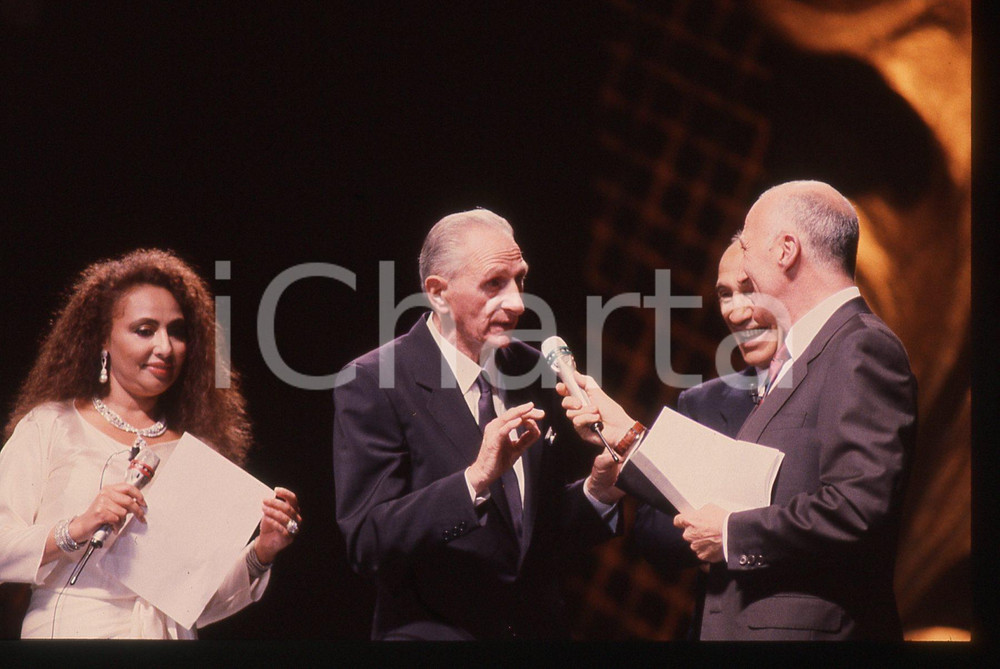 35mm vintage slide* 1990 MILANO Silvio PIOLA Lara SAINT PAUL Galà  ITALIA '90 La manifestazione si &egrave; tenuta presso il PalatrussardiDiapositiva d'epoca, in formato 35 mm. CONDIZIONI: GOODE' severamente vietata la riproduzione. Tutti i diritti sono riservati. ICharta mette in vendita, sul negozio eBay e in esclusiva sul sito "icharta" il proprio archivio composto da numerose diapositive e negativi fotografici d'epoca, tutti originali e autentici, che attraversano la storia del costume italiano tra gli la fine degli anni Sessanta e Novanta.Si tratta di uno sguardo inedito sull'attualit&agrave;, la politica, la vita quotidiana, il gossip e la cultura, che fotografa il cambiamento della nazione in quest'ultimo scorcio del XX secolo. Un'occasione unica per il mercato del collezionismo, che vede finalmente disponibile un archivio eccezionale per vastit&agrave;, tematiche e condizioni, in un settore (il negativo fotografico e la diapositiva) di assoluta novit&agrave; e dalle interessanti prospettive di investimento.  originale e autentica 1