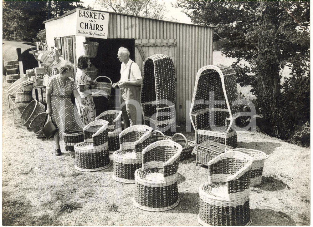1957 SOMERSET ENGLAND - Craftsman sells his basket chairs to travellers *Photo