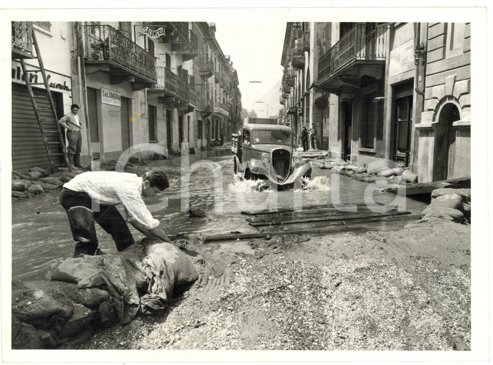 1957 ALLUVIONE BUSSOLENO (TO) Operaio getta sabbia in una strada allagata *Foto