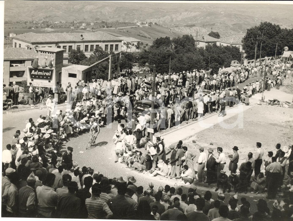 1955 ca CICLISMO GIRO D'ITALIA Passaggio della corsa tra la folla di un paese Fotografia d'epoca con didascalia coeva. CONDIZIONI: G FORMATO: 18x13 cm      originale e autentica 1