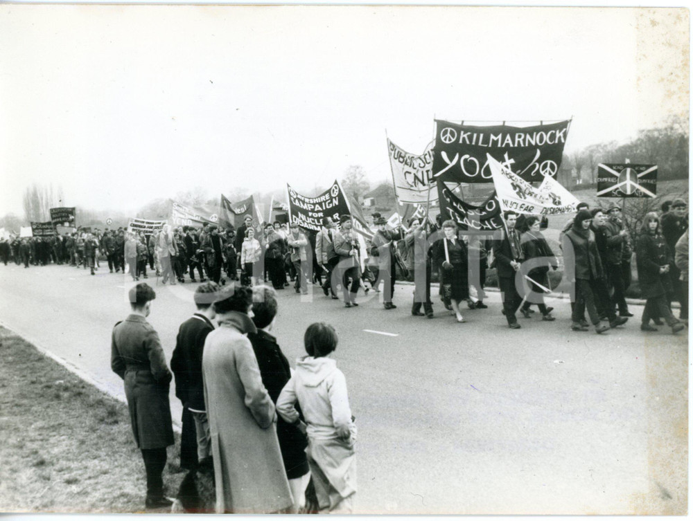 1962 ALDEMARSTON MARCH - CND supporters marching from READING to SLOUGH *Photo  Fotografia d'epoca con didascalia dattiloscritta coeva.   CONDIZIONI: POOR (sovraimpressione del timbro al margine inferiore, increspature al centro, bruniture al margine superiore, resti di colla al margine destro) FORMATO: 18x13 cm      originale e autentica 1