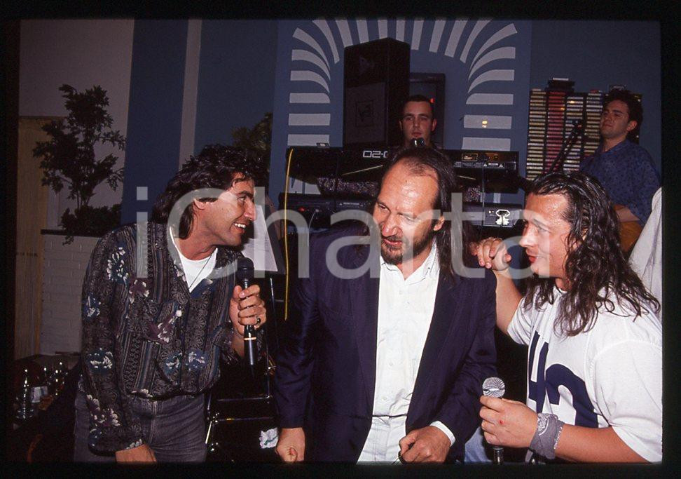 35mm vintage slide* 1991 MUSICA  Andrea MINGARDI Luciano LIGABUE   e Paolo BELLI    Diapositiva d'epoca, in formato 35 mm.  CONDIZIONI: GOOD E' severamente vietata la riproduzione. Tutti i diritti sono riservati.Nella diapositiva ICharta mette in vendita, sul negozio eBay e in esclusiva sul sito "icharta" il proprio archivio composto da numerose diapositive e negativi fotografici d'epoca, tutti originali e autentici, che attraversano la storia del costume italiano tra gli la fine degli anni Sessanta e Novanta.Si tratta di uno sguardo inedito sull'attualit&agrave;, la politica, la vita quotidiana, il gossip e la cultura, che fotografa il cambiamento della nazione in quest'ultimo scorcio del XX secolo. Un'occasione unica per il mercato del collezionismo, che vede finalmente disponibile un archivio eccezionale per vastit&agrave;, tematiche e condizioni, in un settore (il negativo fotografico e la diapositiva) di assoluta novit&agrave; e dalle interessanti prospettive di investimento.  CONDIZIONI:GOOD/buono originale e autentica 1