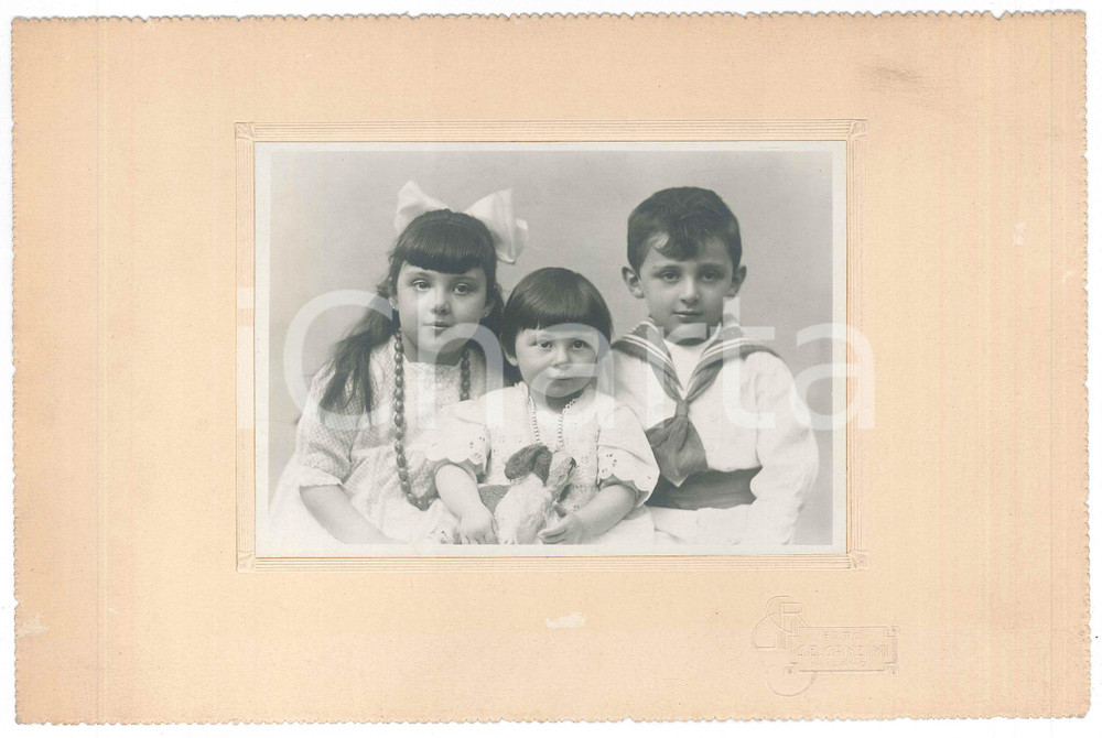 1915 ca MILANO Tre fratellini con pupazzo - Ritratto *Foto G. B. GANZINI 26x18 Fotografia d'epoca, su cartoncino morbido.  GOOD/buono ma piccole abrasioni al cartoncino Formato: 26x18 cm originale e autentica 1