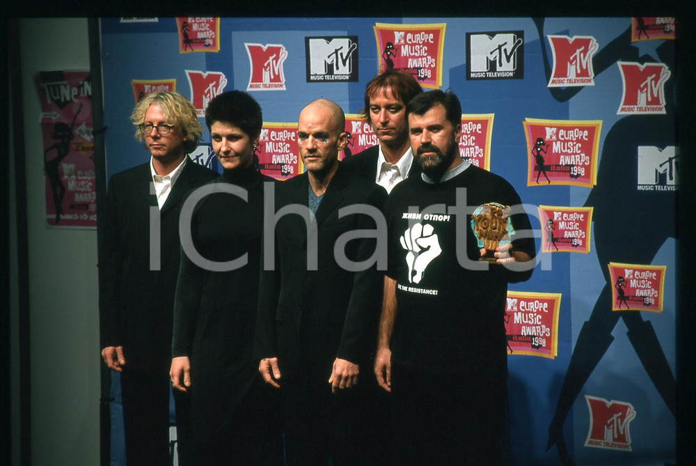 35mm vintage slide* 1988 MTV EMA - B92 Veran MATIC - R.E.M. Michael STIPE  Diapositiva d'epoca, in formato 35 mm.   CONDIZIONI: GOODE' severamente vietata la riproduzione. Tutti i diritti sono riservati. ICharta mette in vendita, sul negozio eBay e in esclusiva sul sito "icharta" il proprio archivio composto da numerose diapositive e negativi fotografici d'epoca, tutti originali e autentici, che attraversano la storia del costume italiano tra gli la fine degli anni Sessanta e Novanta.Si tratta di uno sguardo inedito sull'attualit&agrave;, la politica, la vita quotidiana, il gossip e la cultura, che fotografa il cambiamento della nazione in quest'ultimo scorcio del XX secolo. Un'occasione unica per il mercato del collezionismo, che vede finalmente disponibile un archivio eccezionale per vastit&agrave;, tematiche e condizioni, in un settore (il negativo fotografico e la diapositiva) di assoluta novit&agrave; e dalle interessanti prospettive di investimento.  originale e autentica 1
