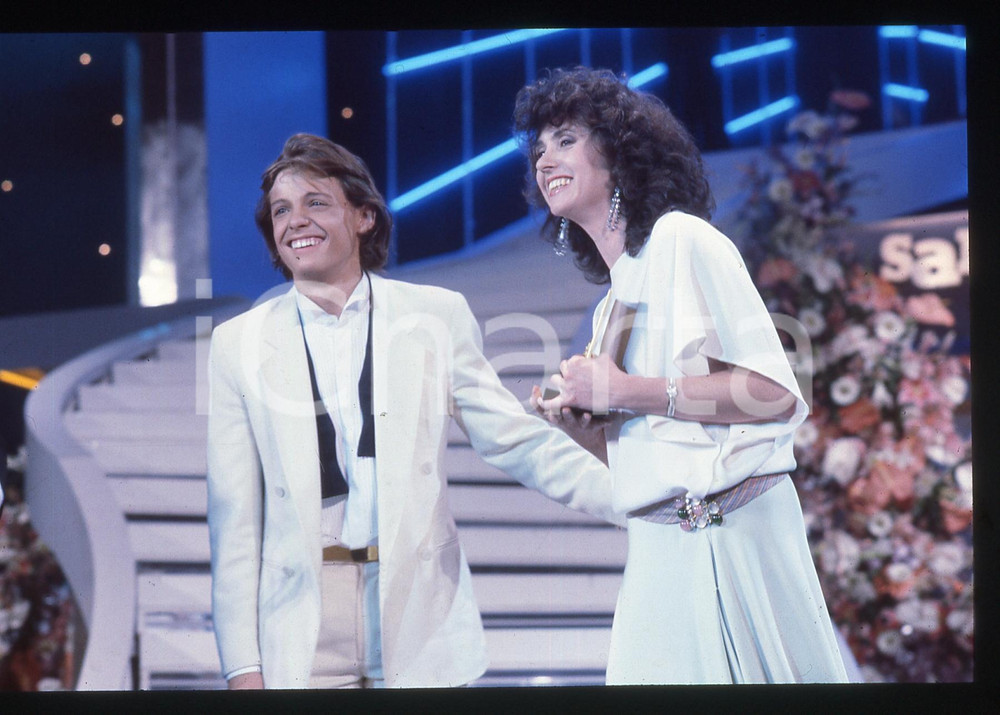 35mm vintage slide* 1985 SANREMO Luis MIGUEL Gigliola CINQUETTI Premiazione Fotografia realizzata alla serata finale del Festival.Diapositiva d'epoca, in formato 35 mm.   CONDIZIONI: GOODE' severamente vietata la riproduzione. Tutti i diritti sono riservati. ICharta mette in vendita, sul negozio eBay e in esclusiva sul sito "icharta" il proprio archivio composto da numerose diapositive e negativi fotografici d'epoca, tutti originali e autentici, che attraversano la storia del costume italiano tra gli la fine degli anni Sessanta e Novanta.Si tratta di uno sguardo inedito sull'attualit&agrave;, la politica, la vita quotidiana, il gossip e la cultura, che fotografa il cambiamento della nazione in quest'ultimo scorcio del XX secolo. Un'occasione unica per il mercato del collezionismo, che vede finalmente disponibile un archivio eccezionale per vastit&agrave;, tematiche e condizioni, in un settore (il negativo fotografico e la diapositiva) di assoluta novit&agrave; e dalle interessanti prospettive di investimento.  originale e autentica 1