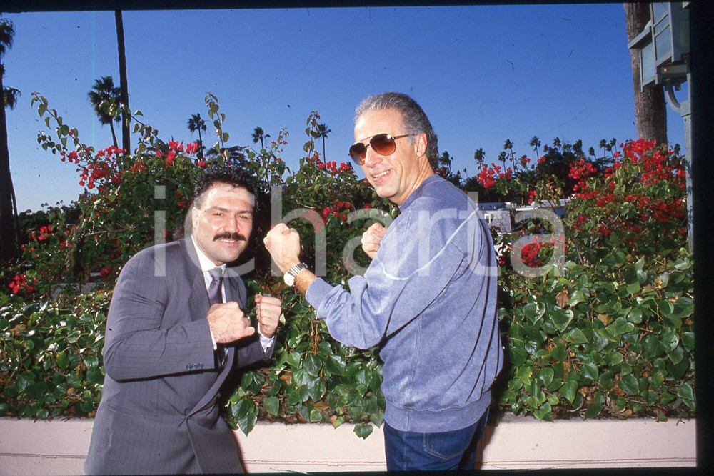 35mm vintage slide* 1985 ca USA Boxer Vinnie CURTO and composer John MADERA (3)  Diapositiva d'epoca, in formato 35 mm.CONDIZIONI: GOODE' severamente vietata la riproduzione. Tutti i diritti sono riservati.Nella diapositiva ICharta mette in vendita, sul negozio eBay e in esclusiva sul sito "icharta" il proprio archivio composto da numerose diapositive e negativi fotografici d'epoca, tutti originali e autentici, che attraversano la storia del costume italiano tra gli la fine degli anni Sessanta e Novanta.Si tratta di uno sguardo inedito sull'attualit&agrave;, la politica, la vita quotidiana, il gossip e la cultura, che fotografa il cambiamento della nazione in quest'ultimo scorcio del XX secolo. Un'occasione unica per il mercato del collezionismo, che vede finalmente disponibile un archivio eccezionale per vastit&agrave;, tematiche e condizioni, in un settore (il negativo fotografico e la diapositiva) di assoluta novit&agrave; e dalle interessanti prospettive di investimento. GOOD/buono   originale e autentica 1