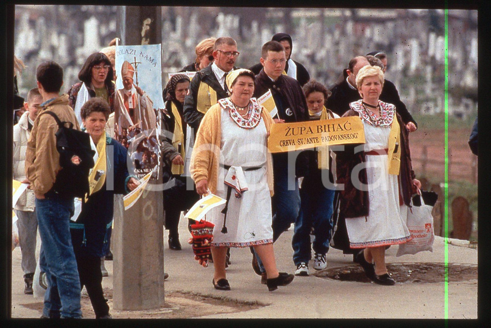 35mm vintage slide 1997 SARAJEVO People going to KOSEVO to see GIOVANNI PAOLO II  Diapositiva d'epoca, in formato 35 mm.CONDIZIONI: GOODE' severamente vietata la riproduzione. Tutti i diritti sono riservati.Nella diapositiva ICharta mette in vendita, sul negozio eBay e in esclusiva sul sito "icharta" il proprio archivio composto da numerose diapositive e negativi fotografici d'epoca, tutti originali e autentici, che attraversano la storia del costume italiano tra gli la fine degli anni Sessanta e Novanta.Si tratta di uno sguardo inedito sull'attualit&agrave;, la politica, la vita quotidiana, il gossip e la cultura, che fotografa il cambiamento della nazione in quest'ultimo scorcio del XX secolo. Un'occasione unica per il mercato del collezionismo, che vede finalmente disponibile un archivio eccezionale per vastit&agrave;, tematiche e condizioni, in un settore (il negativo fotografico e la diapositiva) di assoluta novit&agrave; e dalle interessanti prospettive di investimento.  FAIR/discreto   originale e autentica 1