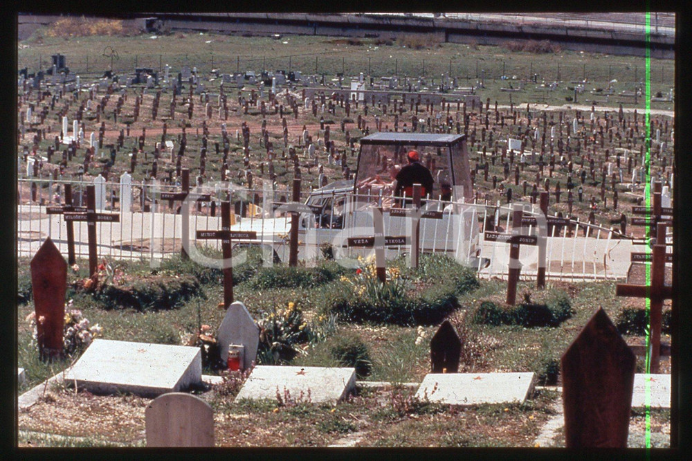 35mm vintage slide*1997 SARAJEVO - GIOVANNI PAOLO II at graveyard  Diapositiva d'epoca, in formato 35 mm.CONDIZIONI: GOODE' severamente vietata la riproduzione. Tutti i diritti sono riservati.Nella diapositiva ICharta mette in vendita, sul negozio eBay e in esclusiva sul sito "icharta" il proprio archivio composto da numerose diapositive e negativi fotografici d'epoca, tutti originali e autentici, che attraversano la storia del costume italiano tra gli la fine degli anni Sessanta e Novanta.Si tratta di uno sguardo inedito sull'attualit&agrave;, la politica, la vita quotidiana, il gossip e la cultura, che fotografa il cambiamento della nazione in quest'ultimo scorcio del XX secolo. Un'occasione unica per il mercato del collezionismo, che vede finalmente disponibile un archivio eccezionale per vastit&agrave;, tematiche e condizioni, in un settore (il negativo fotografico e la diapositiva) di assoluta novit&agrave; e dalle interessanti prospettive di investimento.  FAIR/discreto   originale e autentica 1