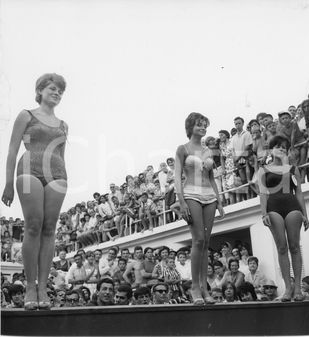 1961 ALASSIO Concorso di bellezza in un lido - Miss in passerella - Foto (1) 1961Fotografia vintage rara d'epoca.Timbro archivio Publifoto Genova al verso.FORMATO: 18x19 cm CONDIZIONI: POOR (sbrecciatura e residuo cartaceo al lato sinistro)ICHARTA mette in vendita le stampe vintage della collezione Publifoto Genova, per la maggior parte inedita o in tiratura di pochi esemplari. Si tratta di un'ottima opportunit&agrave; di investimento per i collezionisti di fotografie d'epoca.    originale e autentica 1