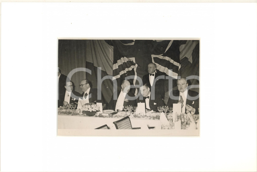 1948 BRUXELLES Chambre de Commerce Britannique - Banquet - Photo 30x20 cm  Fotografia d'epoca, incorniciata con passepartout in cartoncino pesante e fissata con adesivo al retro.La fotografia reca al verso la didascalia originale dell'epoca.CONDIZIONI: POOR (piegatura trasversale alla fotografia, con minima sbrecciatura centrale)FORMATO: 18x13 cm (fotografia); 30x20 cm (cartoncino)    originale e autentica 1