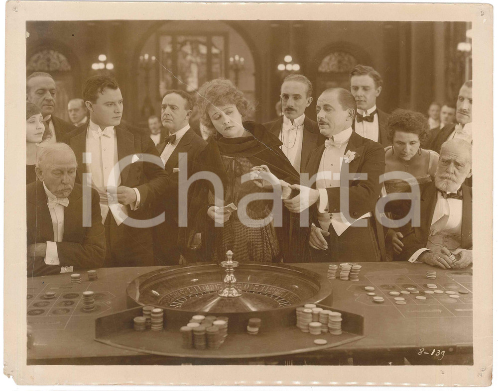 1921 USA Silent film "Without limit" - Roulette scene - DAMAGED Set photo (5) Fotografia originale d'epoca, con didascalia al verso. VERY POOR/gravemente danneggiato piccoli fori angolari; piegature evidenti; danni da umidità ai margini; piccoli strappi e mancanza Formato: 26x20 cm originale e autentica 1