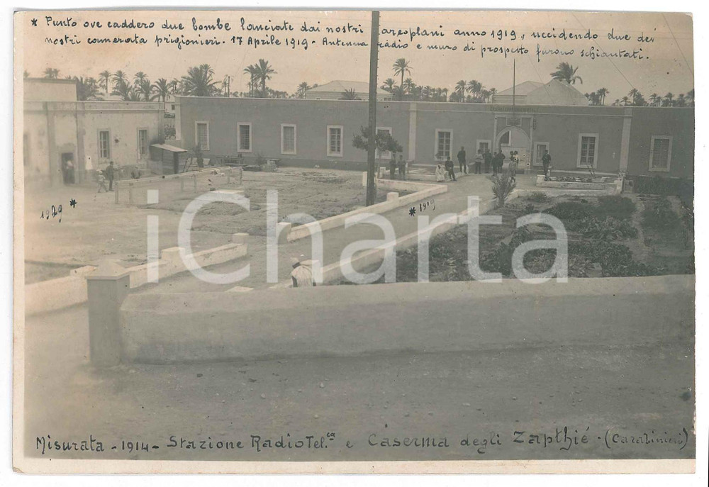 1914 MISURATA (LIBIA) Stazione Radiotelegrafica e Caserma Zapthiè (Carabinieri) Fotografia d'epoca, con didascalia manoscritta al recto.La didascalia in basso, datata 1919, serve a specificare la natura degli asterischi disegnati sulla foto, ovvero marcare i "punti ove caddero due bombe lanciate dai nostri aeroplani anno 1919, uccidendo due dei nostri camerata prigionieri. 17 Aprile 1919. Antenna radio e muro di prospetto furono schiantati".FOTOGRAFO: Silvio Fachinotti FAIR/discreto lievi abrasioni al verso Formato: 17x11 cm originale e autentica 1