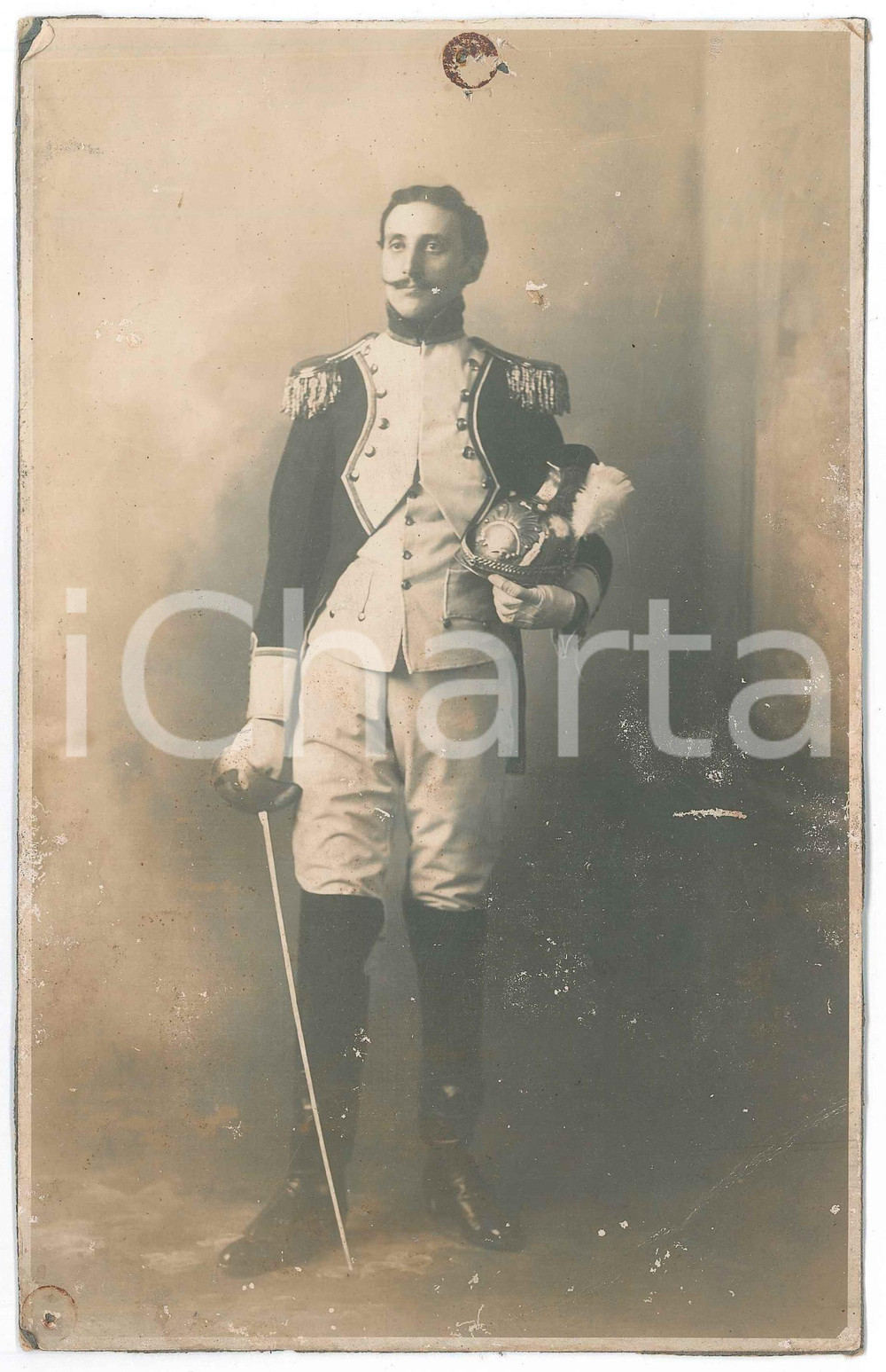 1900 ca ITALIA REGIO ESERCITO Ufficiale con elmo - Fotografia 15x23 cm  Fotografia d'epoca, su cartoncino rigido. VERY POOR/gravemente danneggiato fori marginali con tracce di ruggine e ampia piegatura angolare Formato: 15x23 cm originale e autentica 1