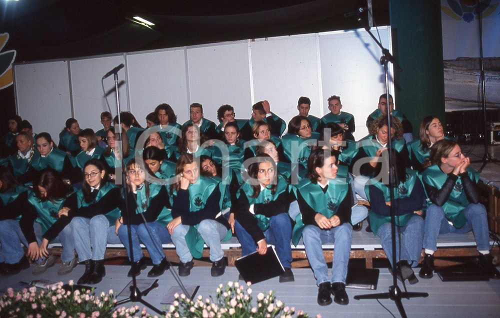 35mm vintage slide* 1999  GRANDE MEETING SANREMO il coro sul palco dell'Ariston  Diapositiva d'epoca, in formato 35 mm.CONDIZIONI: GOODE' severamente vietata la riproduzione. Tutti i diritti sono riservati.Nella diapositiva ICharta mette in vendita, sul negozio eBay e in esclusiva sul sito "icharta" il proprio archivio composto da numerose diapositive e negativi fotografici d'epoca, tutti originali e autentici, che attraversano la storia del costume italiano tra gli la fine degli anni Sessanta e Novanta.Si tratta di uno sguardo inedito sull'attualit&agrave;, la politica, la vita quotidiana, il gossip e la cultura, che fotografa il cambiamento della nazione in quest'ultimo scorcio del XX secolo. Un'occasione unica per il mercato del collezionismo, che vede finalmente disponibile un archivio eccezionale per vastit&agrave;, tematiche e condizioni, in un settore (il negativo fotografico e la diapositiva) di assoluta novit&agrave; e dalle interessanti prospettive di investimento. GOOD/buono   originale e autentica 1