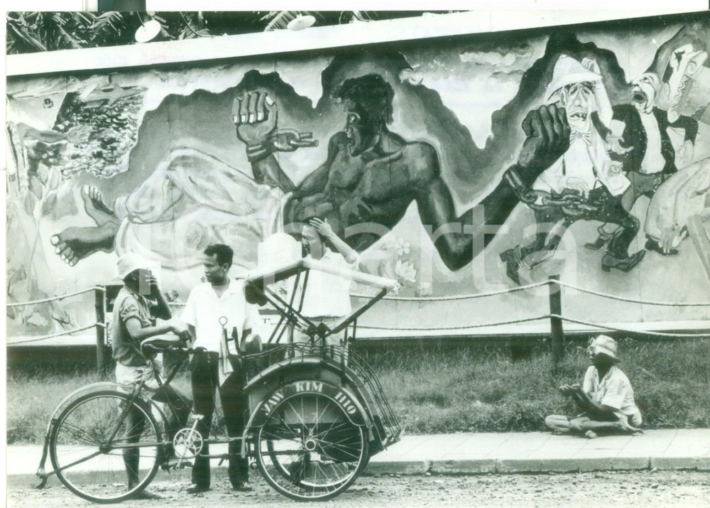 1965 JAKARTA Mendicante chiede carità sotto cartello antimperialista *Foto 18x13