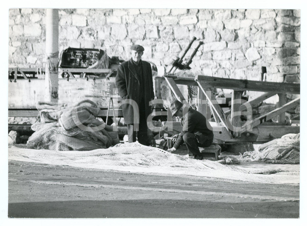 1979 PORTO DI CIVITAVECCHIA Pescatori aggiustano reti da pesca - Foto 17x13 cm Fotografia d'epoca con didascalia al verso.  FAIR/discreto Lievi smussature agli angoli Formato: 17x13 cm originale e autentica 1