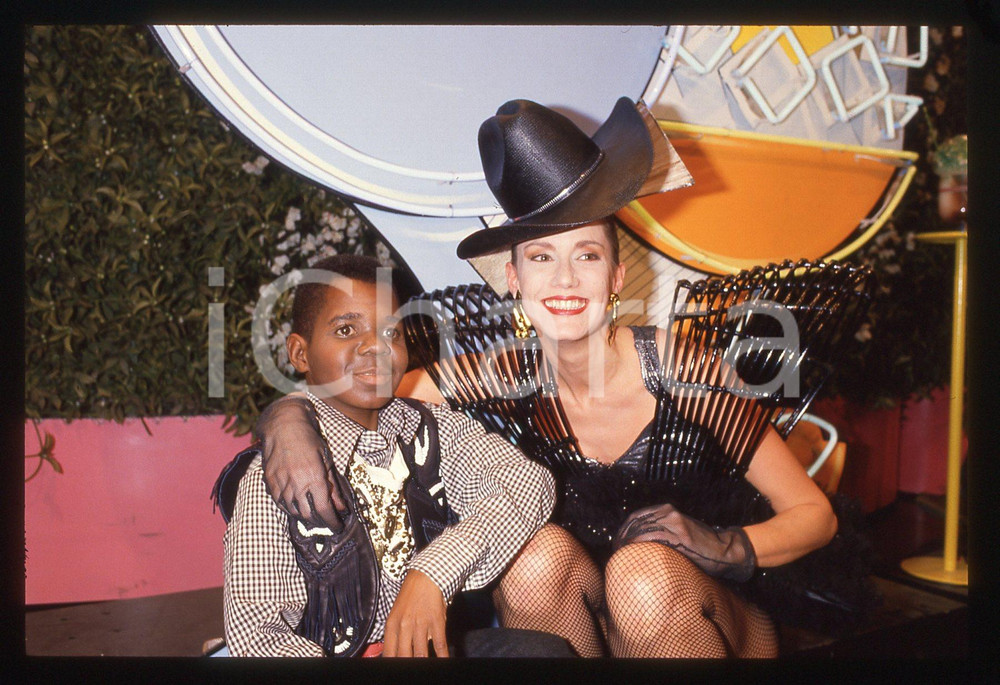 35mm vintage slide* 1985ca DRIVE IN Italia 1 GARY COLEMAN con ragazza Bomber   Diapositiva d'epoca, in formato 35 mm. CONDIZIONI: GOODTutti i diritti riservati.E' severamente vietata la riproduzione. ICharta mette in vendita, sul negozio eBay e in esclusiva sul sito "icharta" il proprio archivio composto da numerose diapositive e negativi fotografici d'epoca, tutti originali e autentici, che attraversano la storia del costume italiano tra gli la fine degli anni Sessanta e Novanta.Si tratta di uno sguardo inedito sull'attualità, la politica, la vita quotidiana, il gossip e la cultura, che fotografa il cambiamento della nazione in quest'ultimo scorcio del XX secolo. Un'occasione unica per il mercato del collezionismo, che vede finalmente disponibile un archivio eccezionale per vastità, tematiche e condizioni, in un settore (il negativo fotografico e la diapositiva) di assoluta novità e dalle interessanti prospettive di investimento.  originale e autentica 1