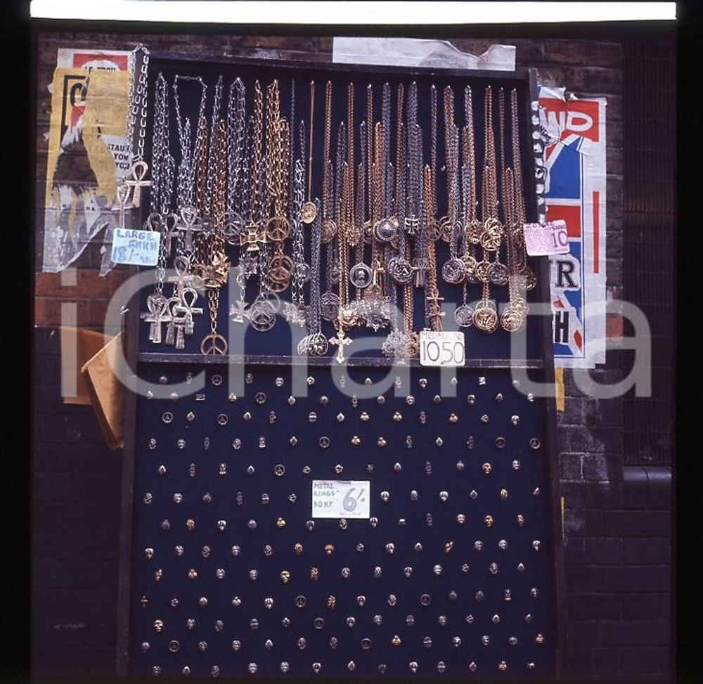 1970ca UK Bancarella con ciondoli  *DIAPOSITIVA ORIGINALE 2   Positivo fotografico originale d'epoca a colori su pellicola  E' SEVERAMENTE VIETATA LA RIPRODUZIONE.TUTTI I DIRITTI SONO RISERVATI.ICharta mette in vendita, sul negozio eBay e in esclusiva sul sito "icharta" il proprio archivio composto da numerose diapositive e negativi fotografici d'epoca, tutti originali e autentici, che attraversano la storia del costume italiano tra gli la fine degli anni Sessanta e Novanta.Si tratta di uno sguardo inedito sull'attualità, la politica, la vita quotidiana, il gossip e la cultura, che fotografa il cambiamento della nazione in quest'ultimo scorcio del XX secolo. Un'occasione unica per il mercato del collezionismo, che vede finalmente disponibile un archivio eccezionale per vastità, tematiche e condizioni, in un settore (il negativo fotografico e la diapositiva) di assoluta novità e dalle interessanti prospettive di investimento. CONDIZIONI:FAIR/discretoFORMATO: cm 6 x 6 originale e autentica 1