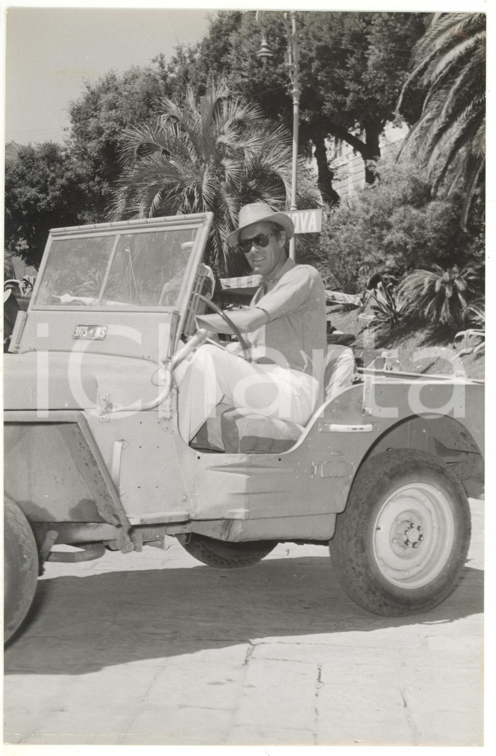 1952 RAPALLO Rex HARRISON su una Jeep nel piazzale della stazione *Foto 15x23 cm Fotografia d'epoca, con didascalia coeva al verso. CONDIZIONI: FAIR (lieve piegatura al margine inferiore)FORMATO: 15x23 cm    originale e autentica 1