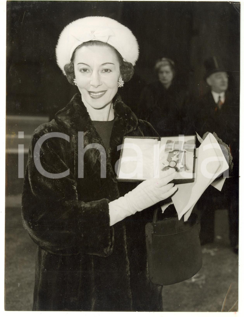 1958 LONDON Prima ballerina Alicia MARKOVA holding the insigna of the C.B.E. Fotografia d'epoca, con didascalia coeva al verso. CONDIZIONI: POOR (piegature ai margini; sovraimpressione al centro)FORMATO: 15x20 cm    originale e autentica 1