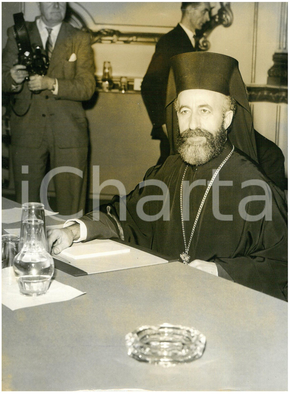 1959 LONDON Lancaster House - Archbishop MAKARIOS III at the conference table Fotografia d'epoca con didascalia coeva al verso.  CONDIZIONI: POOR (alone diffuso; piegature ai margini)     originale e autentica 1