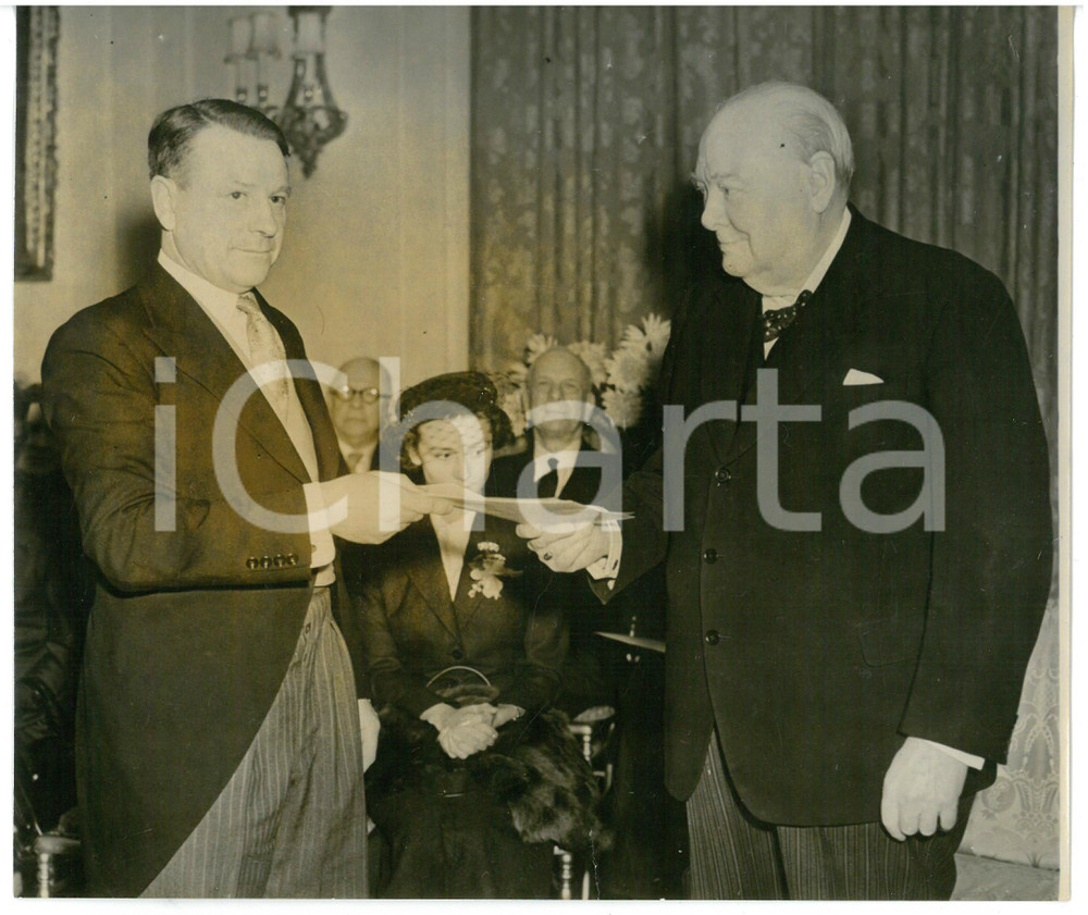 1954 LONDON Sir Winston CHURCHILL receiving birthday cheque by Patrick MOYNIHAN Fotografia d'epoca con didascalia coeva al verso.  CONDIZIONI: POOR (alone diffuso; strappo di circa un centimetro al margine inferiore) CONDIZIONI: 18x15 cm    originale e autentica 1