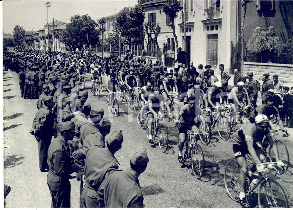 1957 CICLISMO GIRO D'ITALIA Il gruppo nei pressi di Ancona *Fotografia 18x13 cm Fotografia d'epoca con didascalia coeva.  CONDIZIONI: G (ma lieve macchia di inchiostro al margine superiore) FORMATO: 18x13 cm     originale e autentica 1