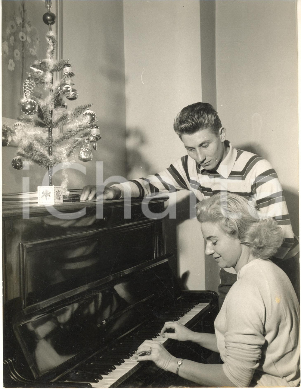 1955 ca CICLISMO Jacques ANQUETIL a Natale con Janine BOEDA al pianoforte (1) Fotografia d'epoca con didascalia coeva al verso. CONDIZIONI: fair (piegatura al lato sinistro; lievi difetti di stampa)FORMATO: 18x24 cm     originale e autentica 1