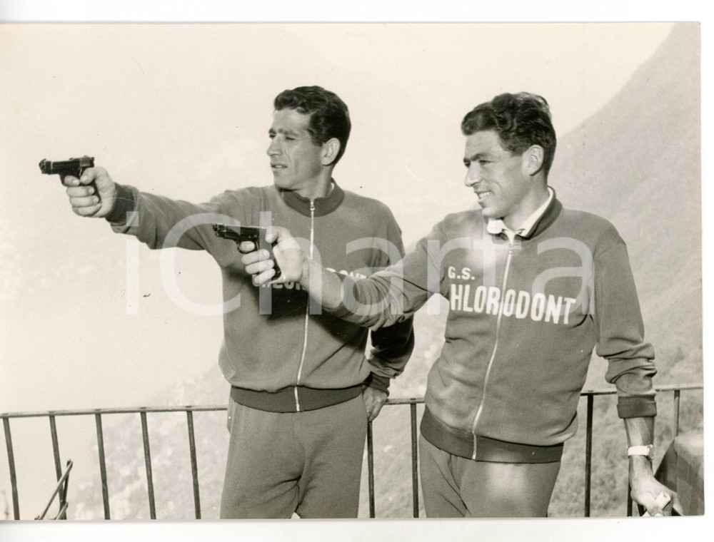 1957 COMO Ciclisti Aldo MOSER e Gastone NENCINI prendono la mira con la pistola Fotografia d'epoca con didascalia coeva al verso. CONDIZIONI: GFORMATO: 18x13 cm     originale e autentica 1