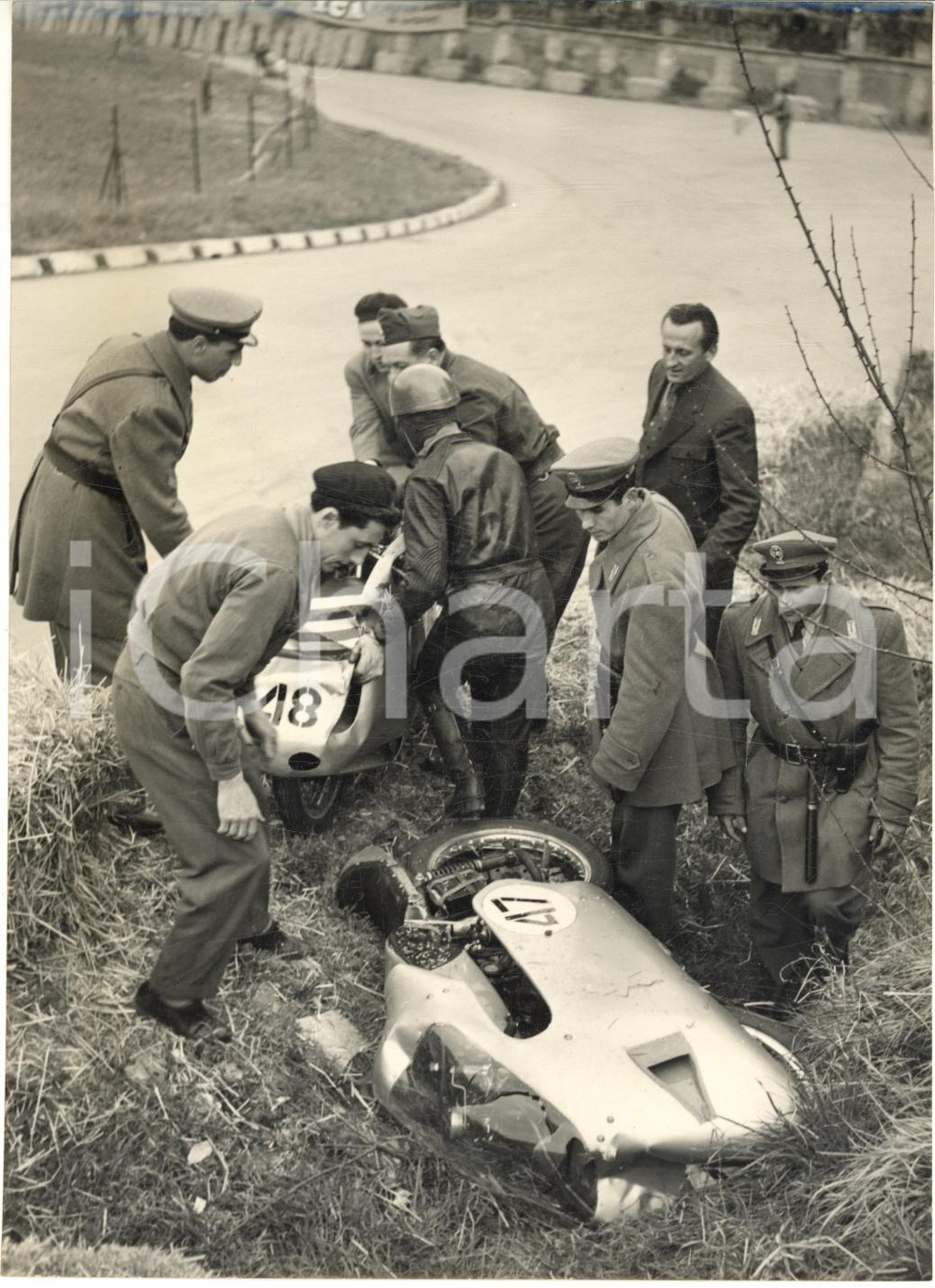1955 MOTOCICLISMO IMOLA Moto di Tarquinio PROVINI e Luigi TAVERI dopo incidente  Fotografia d'epoca con didascalia coeva al verso.   CONDIZIONI: G (ma piccola sovraimpressione circolare al lato destro) FORMATO: 13x18 cm     originale e autentica 1