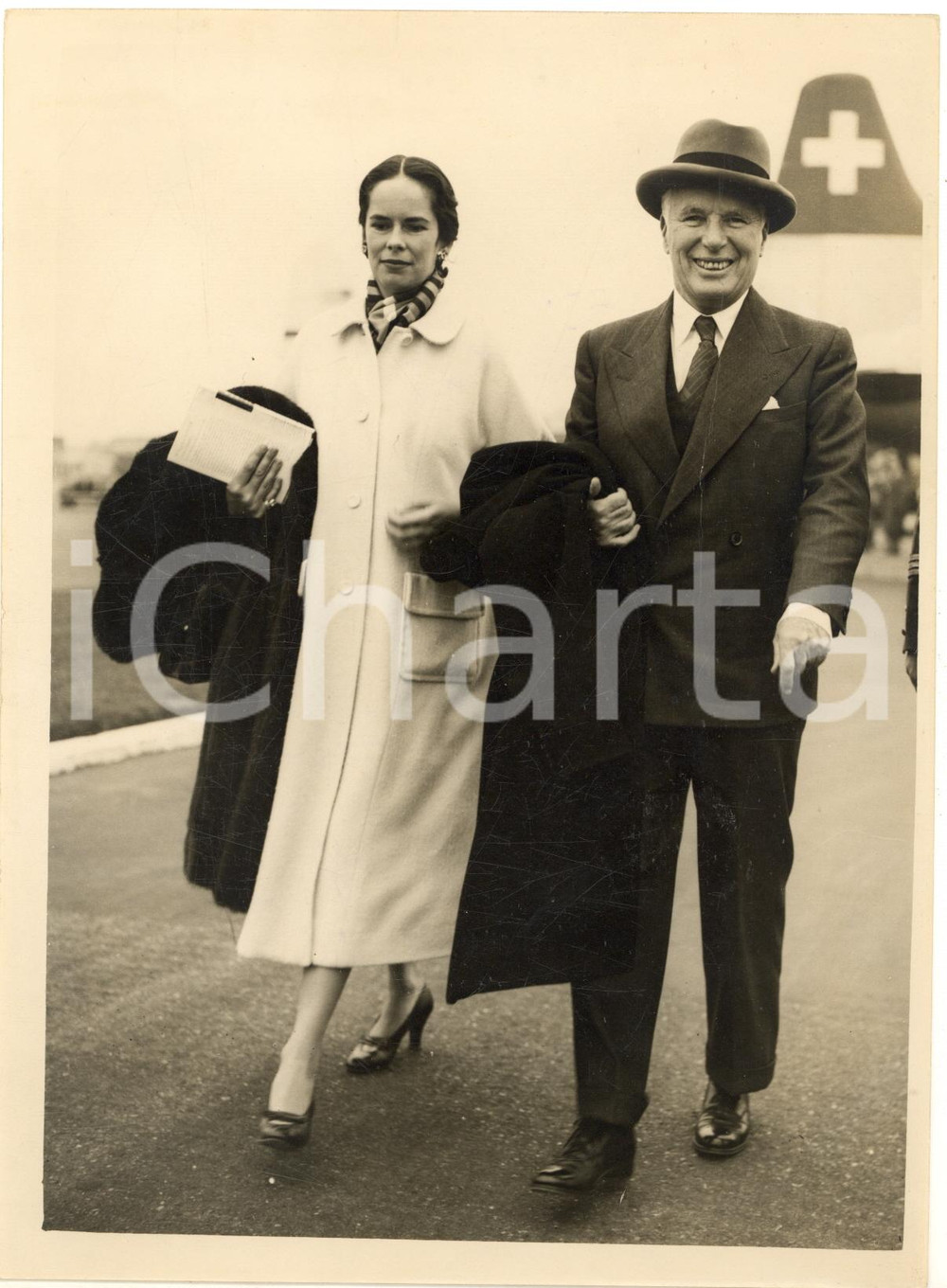 1953 LONDON AIRPORT Charlie CHAPLIN and his wife Oona walking from the aircraft  Fotografia d'epoca con didascalia coeva al verso.   CONDIZIONI: poor (piegature al margine superiore) FORMATO: 15x20 cm     originale e autentica 1