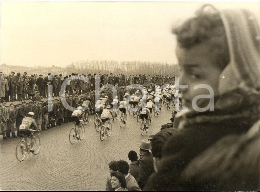 1957 CICLISMO MILANO-SANREMO Passaggio della corsa a Pavia - Foto 18x13 Fotografia d'epoca con didascalia coeva.  CONDIZIONI: FAIR (lieve sovraimpressione al margine inferiore; piccoli difetti di stampa) FORMATO: 18x13 cm     originale e autentica 1