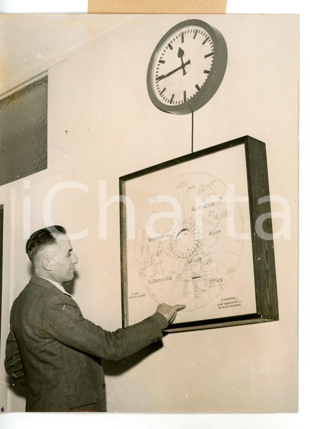 1954 BERLIN Giornalista consulta "orologio mondiale" - Fotografia 15x20 cm Fotografia d'epoca con didascalia coeva.  CONDIZIONI: FAIR (alone diffuso; difetti di stampa; piccole piegature ai margini) FORMATO: 15x20 cm     originale e autentica 1