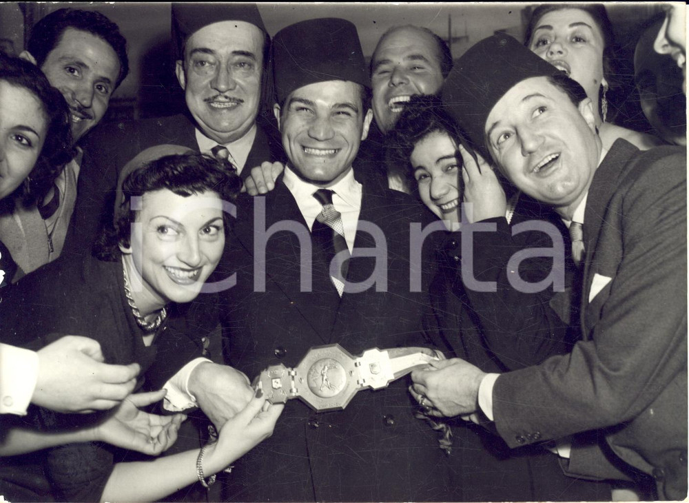 1958 PARIS Boxeur Robert COHEN champion d'Europe en "chÃ©chia" *Photo 18x13 Fotografia d'epoca con didascalia coeva al verso.Nella foto sono presenti anche Maria Murano e Andr&eacute; Dassary.  CONDIZIONI: fair (sovraimpressione circolare) FORMATO: 18x13 cm    originale e autentica 1