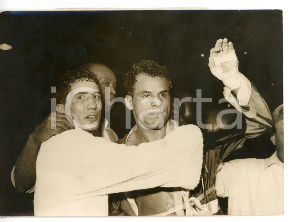 1957 PARIS BOXE Seraphin FERRER e Ralph DUPAS al termine del match *Foto 18x13 Fotografia d'epoca con didascalia coeva.  CONDIZIONI: G (ma lieve alone diffuso; piccola piegatura al margine sinistro) FORMATO: 18x13 cm     originale e autentica 1