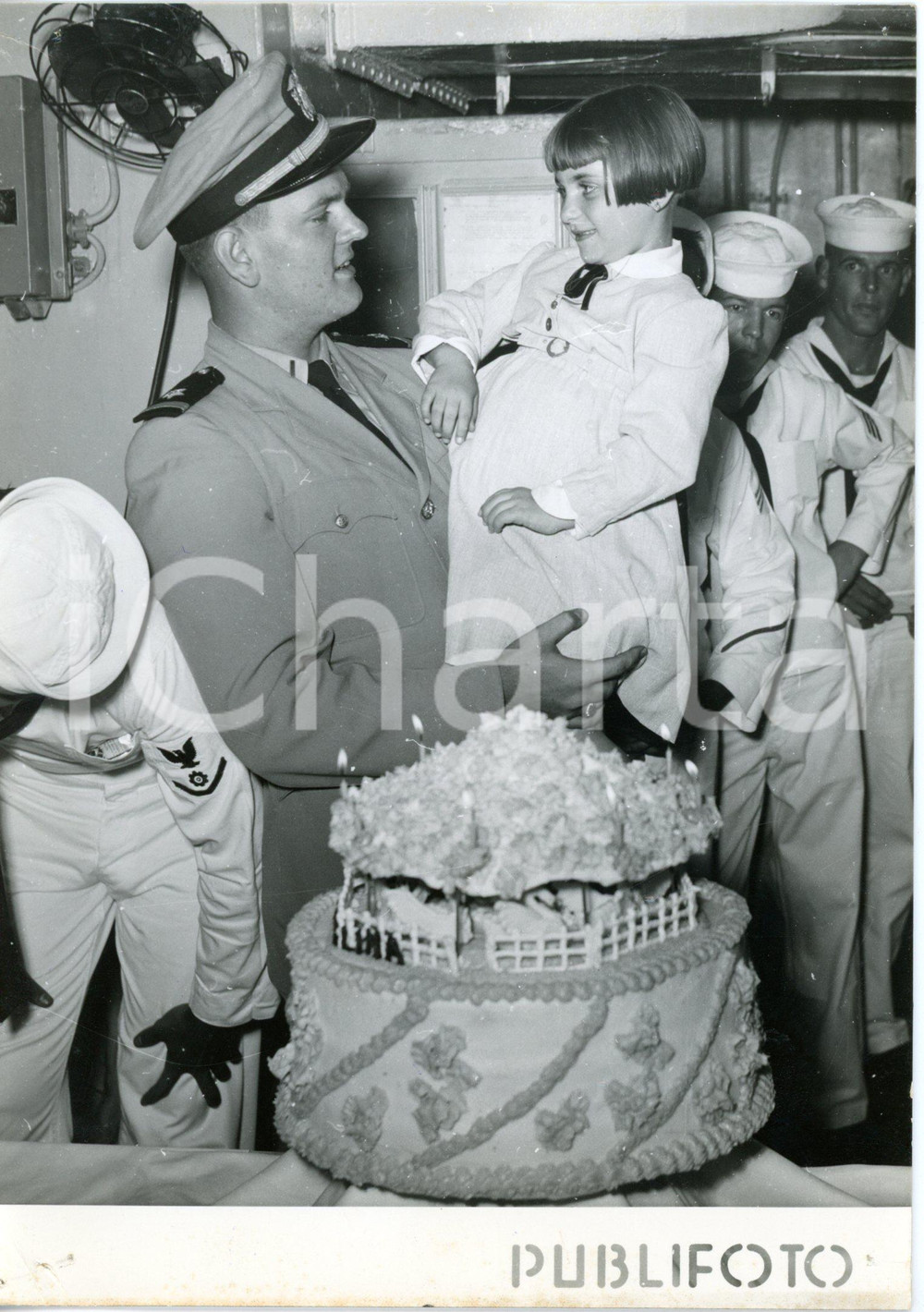 1957 NAPOLI USS Capricornus - Equipaggio festeggia adozione di Carmelina RUSSO  Fotografia d'epoca con didascalia dattiloscritta coeva.  CONDIZIONI: POOR (forellini da graffetta e piegatura all'angolo inferiore sinistro, sovraimpressione verticale al margine destro, bruniture al margine inferiore, difetti di stampa) FORMATO: 13x18 cm     originale e autentica 1