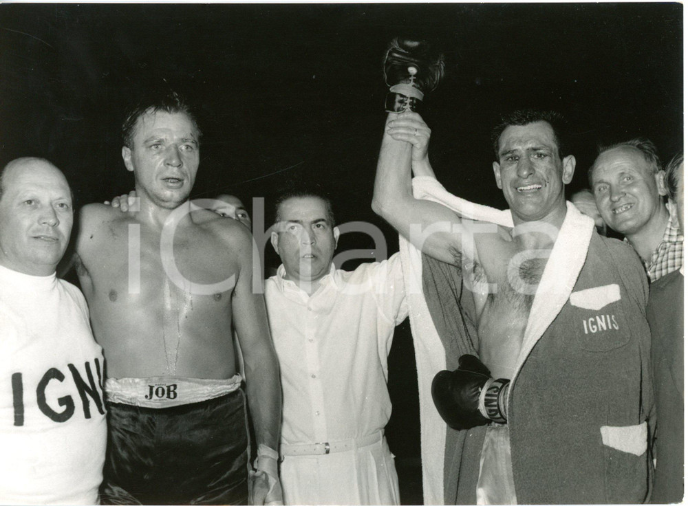1957 MILANO - BOXE - Artemio CALZAVARA vince il titolo europeo pesi mediomassimi  Fotografia d'epoca con didascalia dattiloscritta coeva, scattata presso il Velodromo Vigorelli. Nella fotografia &egrave; presente anche Gerhard Hecht. CONDIZIONI: FAIR (sovraimpressioni al margine inferiore, graffio al margine sinistro, piegatura al margine destro e all'angolo inferiore sinistro, difetti di stampa) FORMATO: 15x20 cm     originale e autentica 1